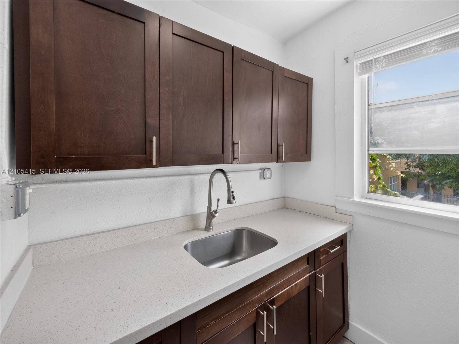 967 SW 5th Street, #11, Miami, Miami, FL 33130 Dark wood-finish cabinetry, solid surface countertop, stainless steel undermount sink, gooseneck faucet, and window with built-in blinds