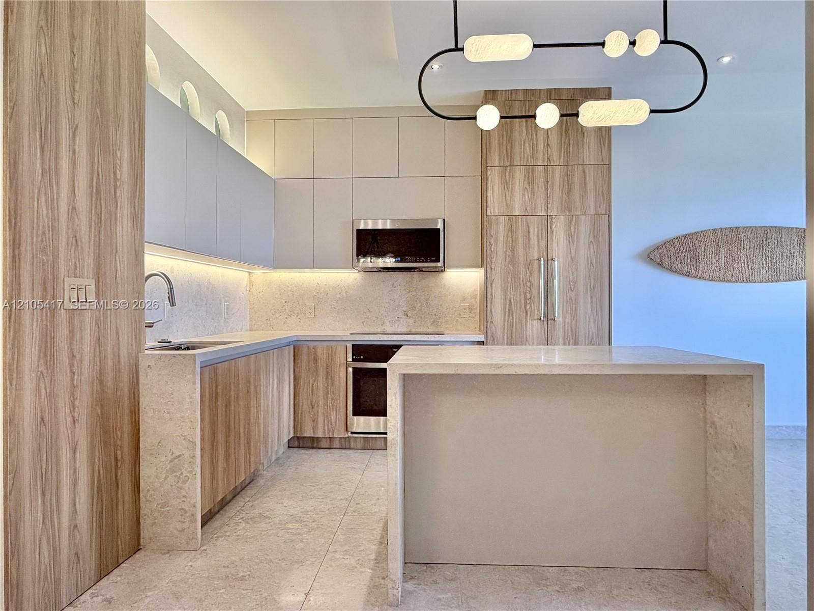 Kitchen featuring wood-finish cabinetry, stainless steel appliances, stone countertops, and an integrated island
