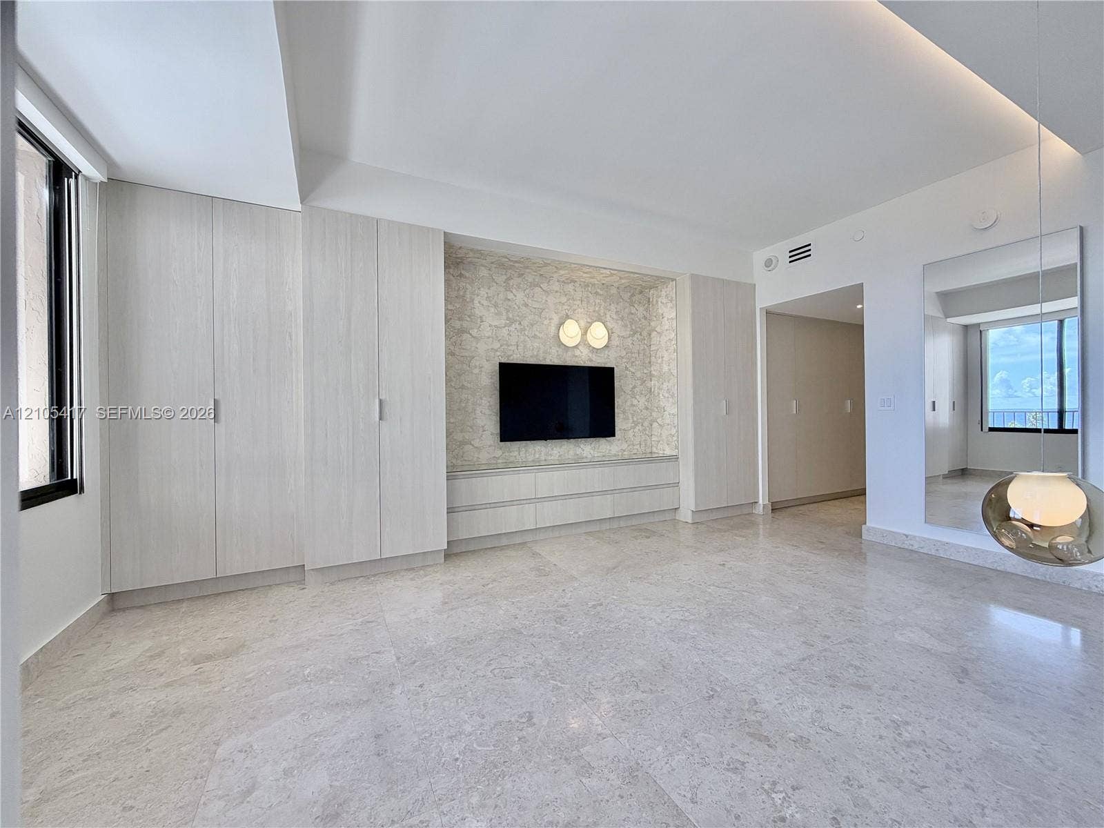 Light-toned tile flooring, built-in light wood-finish cabinetry, and a recessed entertainment area with accent lighting