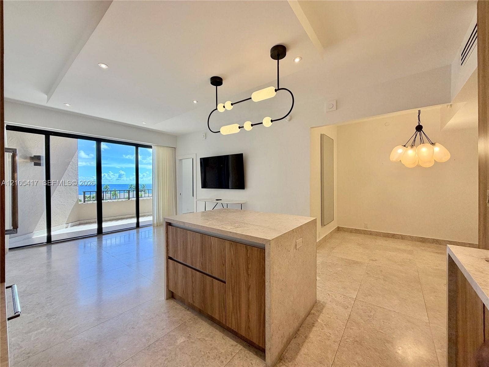 Expansive sliding glass doors, built-in kitchen island with stone countertop, and recessed lighting