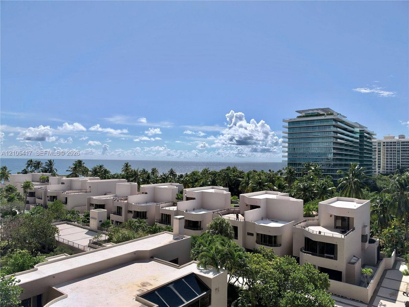Modern low-rise buildings with multiple balconies, surrounded by lush tropical landscaping