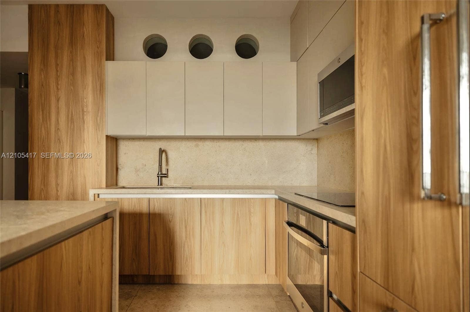 Kitchen featuring wood-finish cabinetry, light-toned countertops, integrated sink with a modern faucet, built-in oven, and a flat-surface cooktop