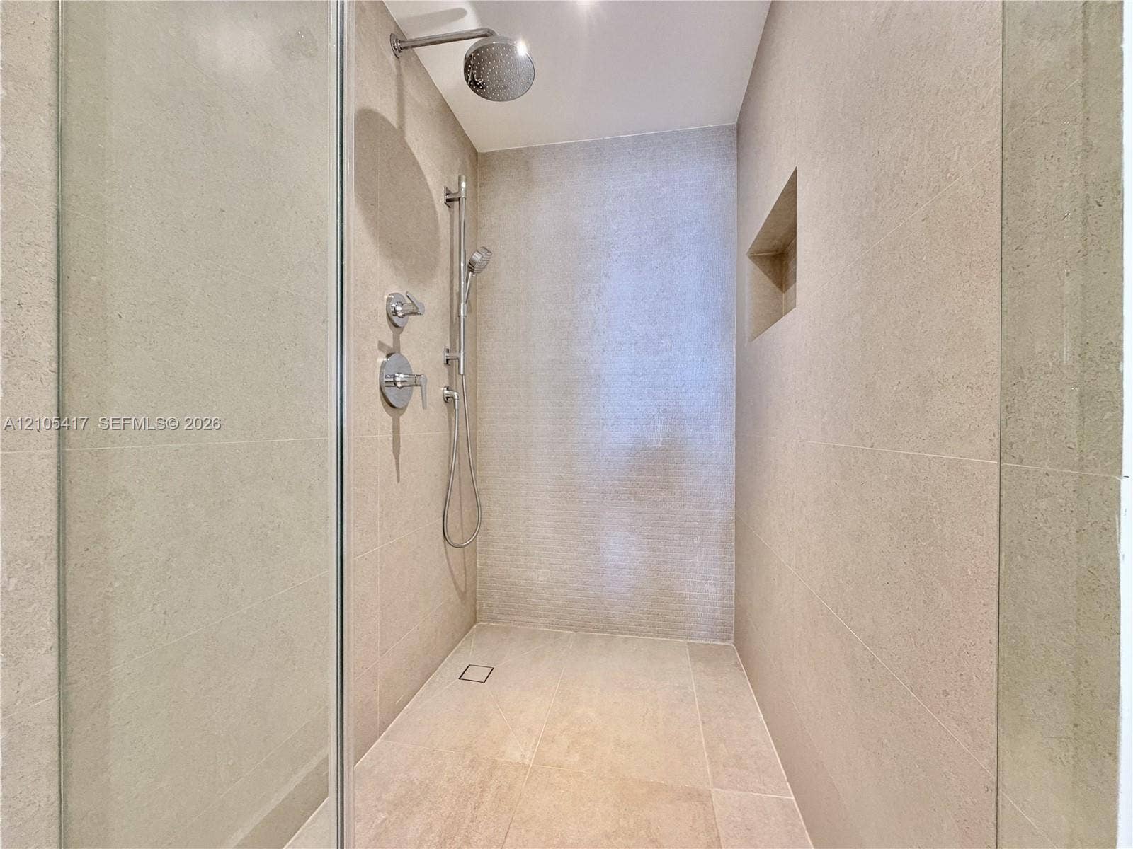Walk-in shower with full-height tile, recessed niche, rainfall showerhead, and handheld shower fixture