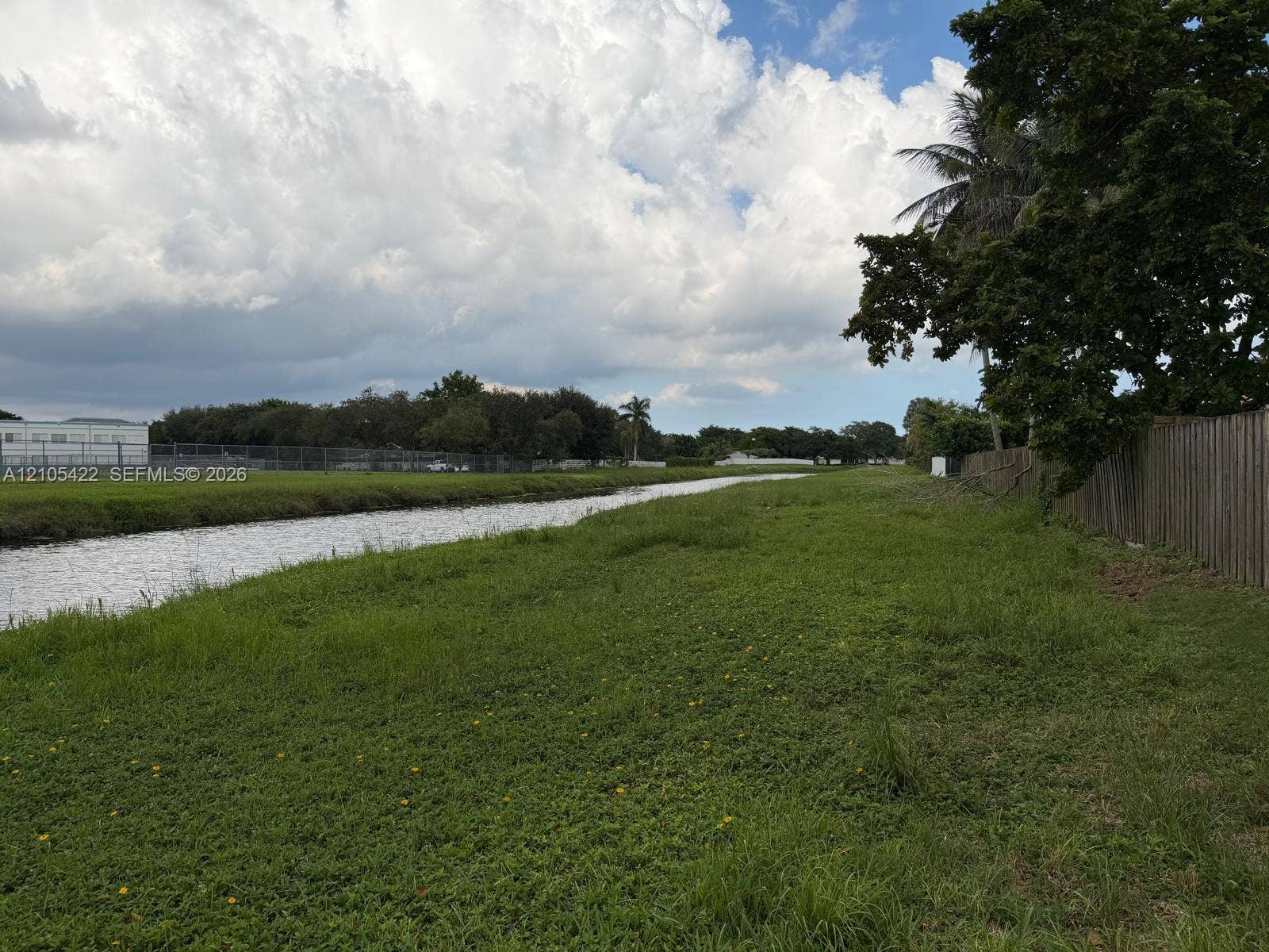 14631 SW 150th Street, Miami, FL 33186 Waterfront parcel featuring open green space, mature trees, and wooden perimeter fencing