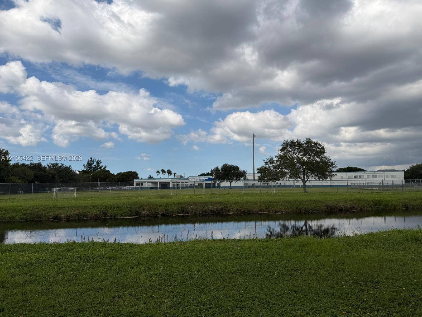 14631 SW 150th Street, Miami, FL 33186 Open green space featuring a natural water element, perimeter fencing, and mature trees