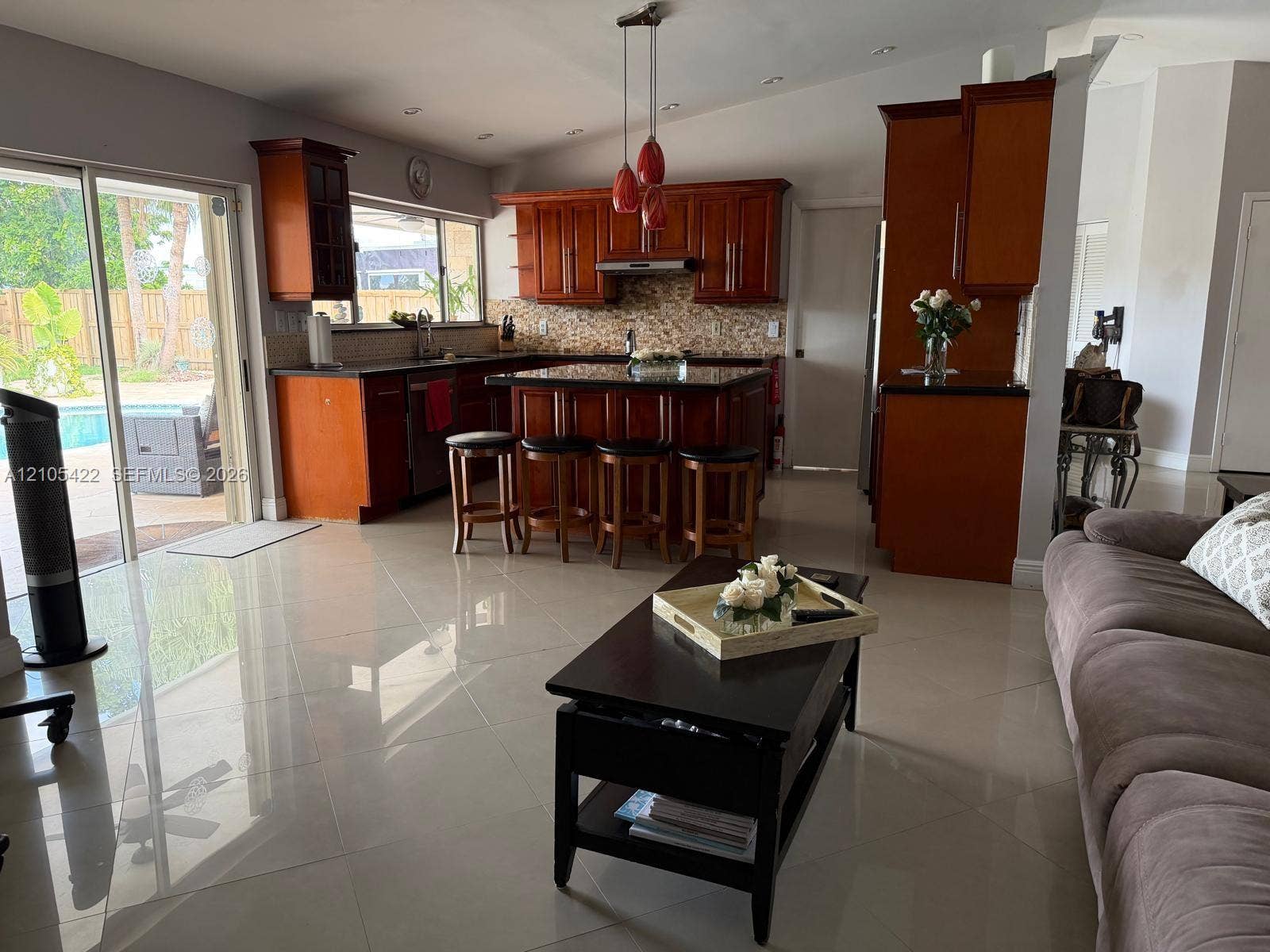 14631 SW 150th Street, Miami, FL 33186 Kitchen featuring cherry-finish cabinetry, central island with seating, stone-tiled backsplash, recessed lighting, and large-format porcelain tile flooring