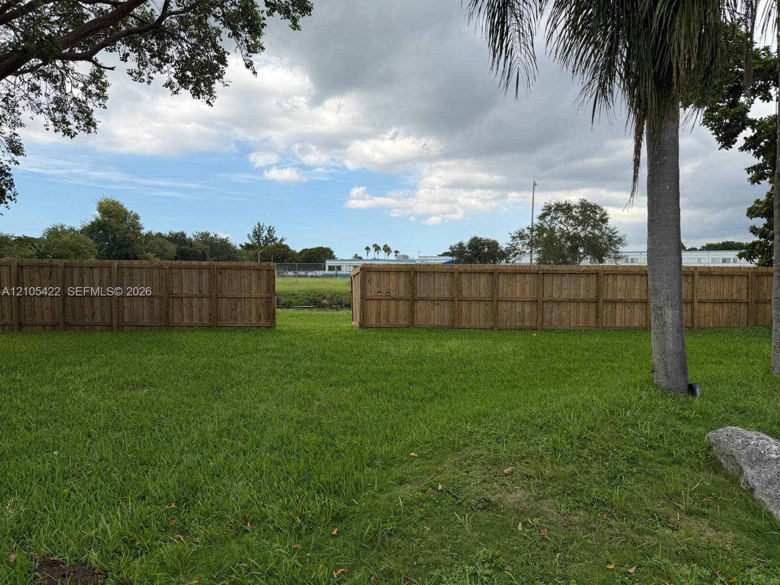 14631 SW 150th Street, Miami, FL 33186 Expansive backyard featuring a grass lawn, mature trees, and a wooden privacy fence