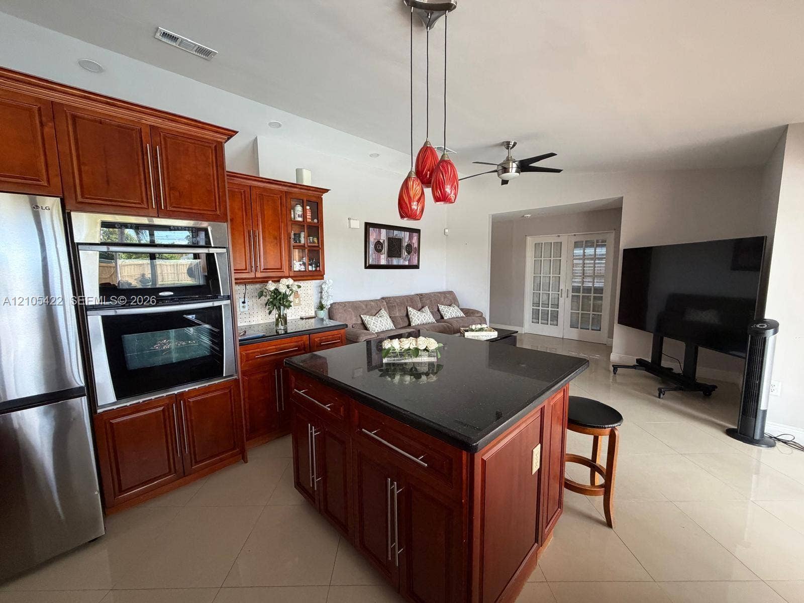 14631 SW 150th Street, Miami, FL 33186 Kitchen featuring wooden cabinetry, central island with stone countertop, stainless steel double wall oven, and three-pendant lighting