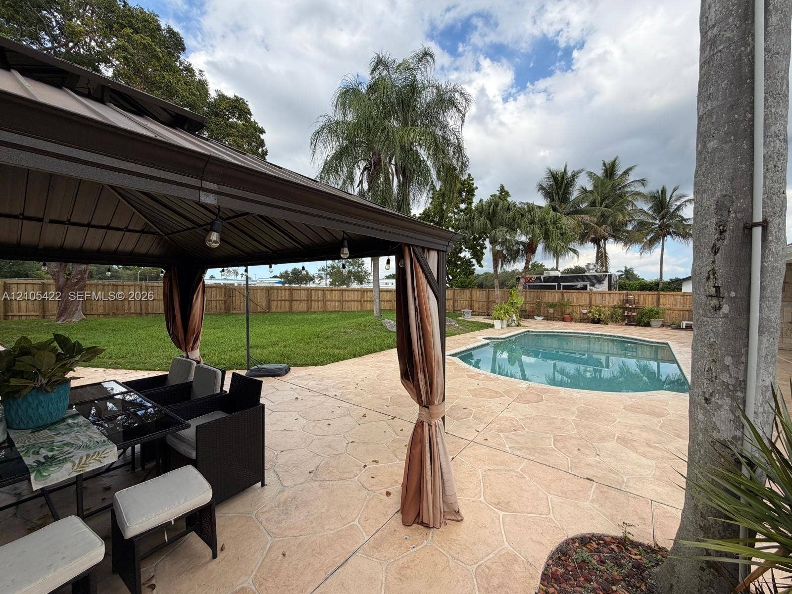 14631 SW 150th Street, Miami, FL 33186 Backyard featuring a metal-frame gazebo, stamped concrete patio, inground swimming pool, and privacy wood fencing