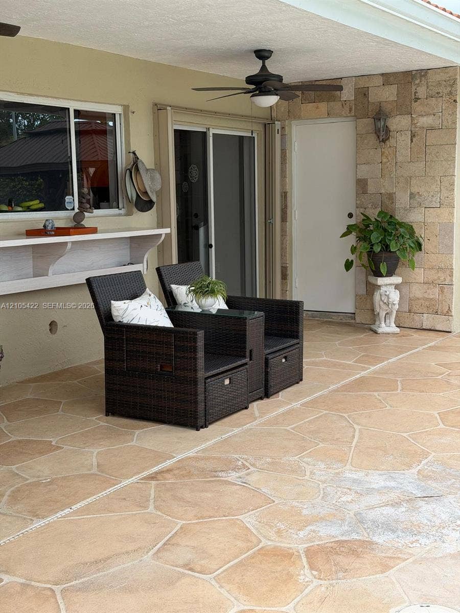 14631 SW 150th Street, Miami, FL 33186 Covered patio featuring flagstone flooring, a natural stone veneer accent wall, built-in shelving, and a ceiling-mounted fan