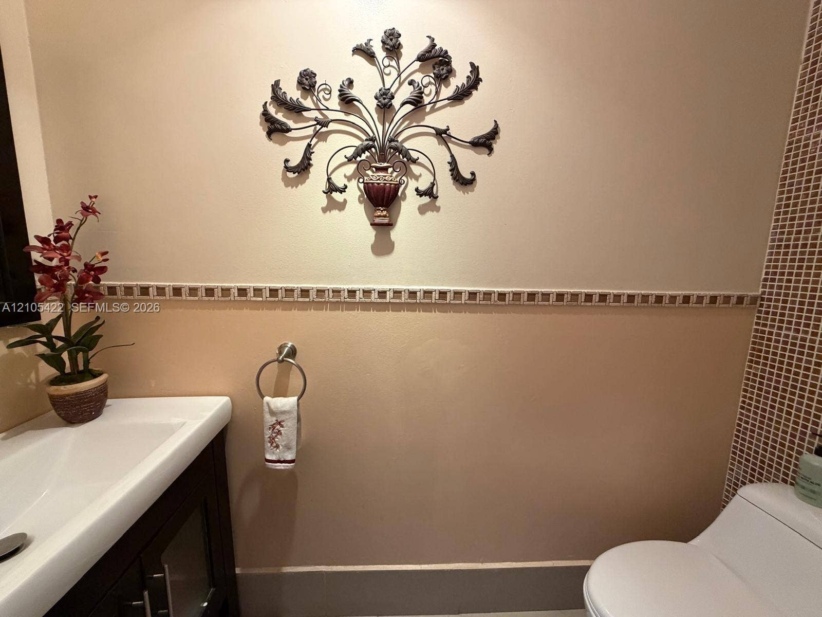 14631 SW 150th Street, Miami, FL 33186 Wall-mounted vanity featuring a white basin, two-toned wall paint, decorative tile border inlay, and small-format mosaic wall tile