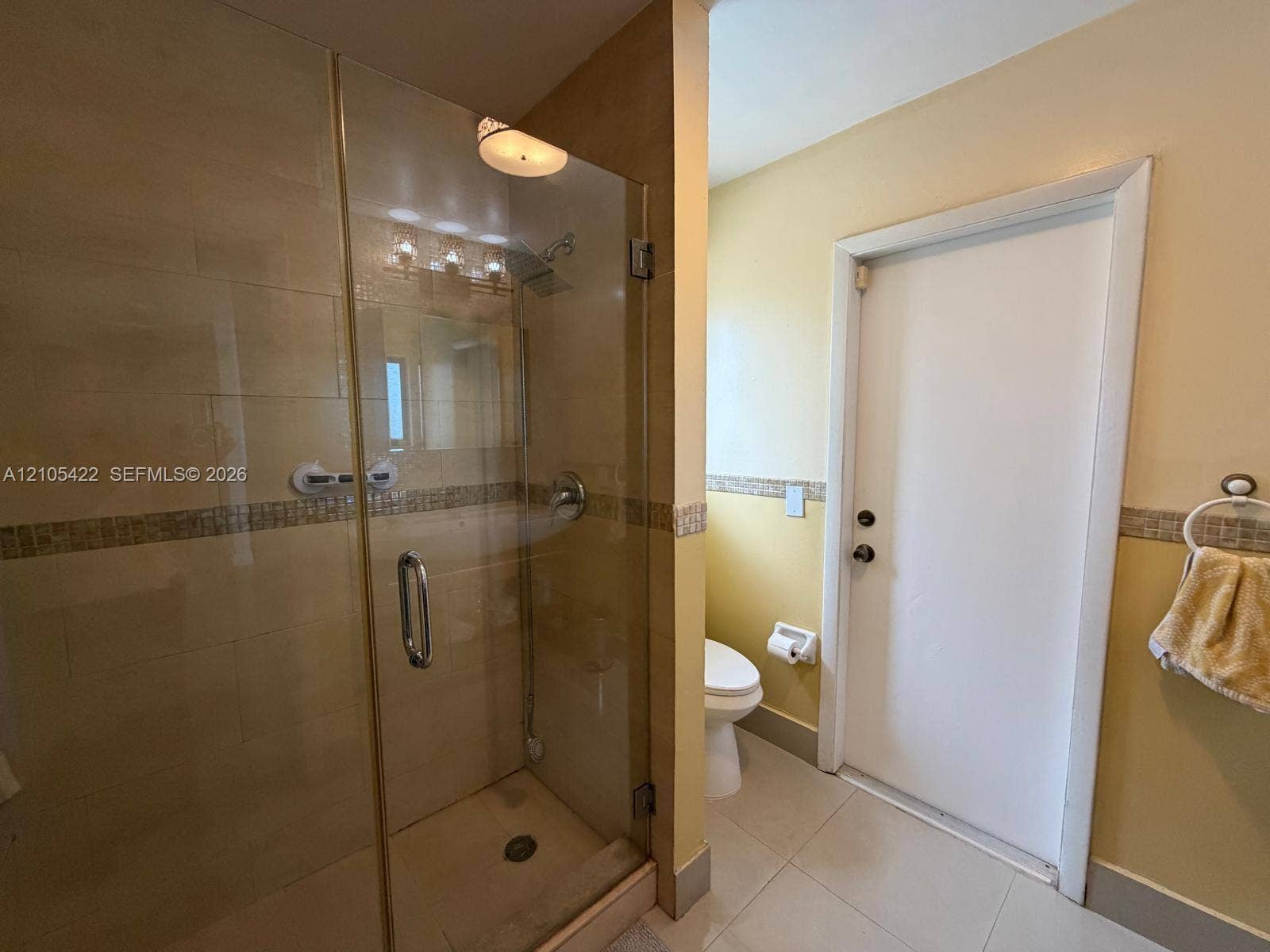 14631 SW 150th Street, Miami, FL 33186 Walk-in shower with a glass enclosure, tile surround, decorative mosaic tile inlay, and integrated plumbing fixtures, featuring large-format tile flooring