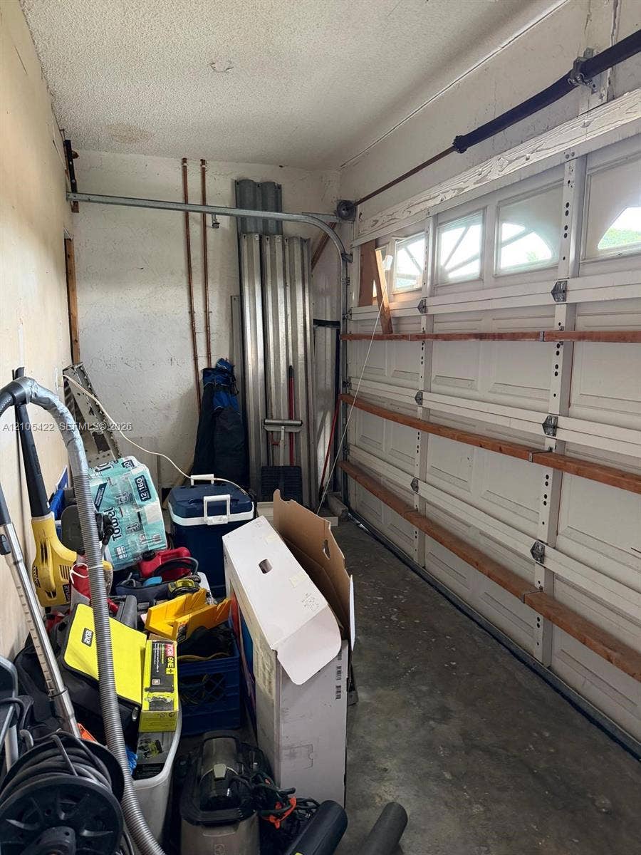 14631 SW 150th Street, Miami, FL 33186 Garage interior featuring a sectional roll-up door with windows and exposed structural framing