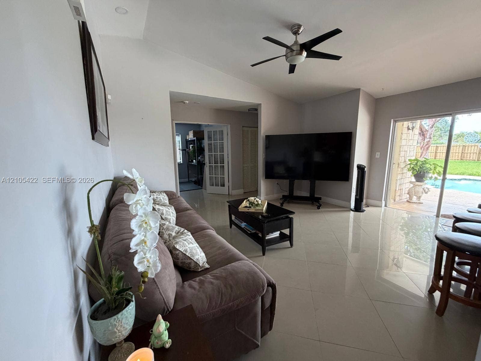 14631 SW 150th Street, Miami, FL 33186 Living space featuring polished tile flooring, vaulted ceilings, a brushed nickel ceiling fan, and sliding glass doors with patio access