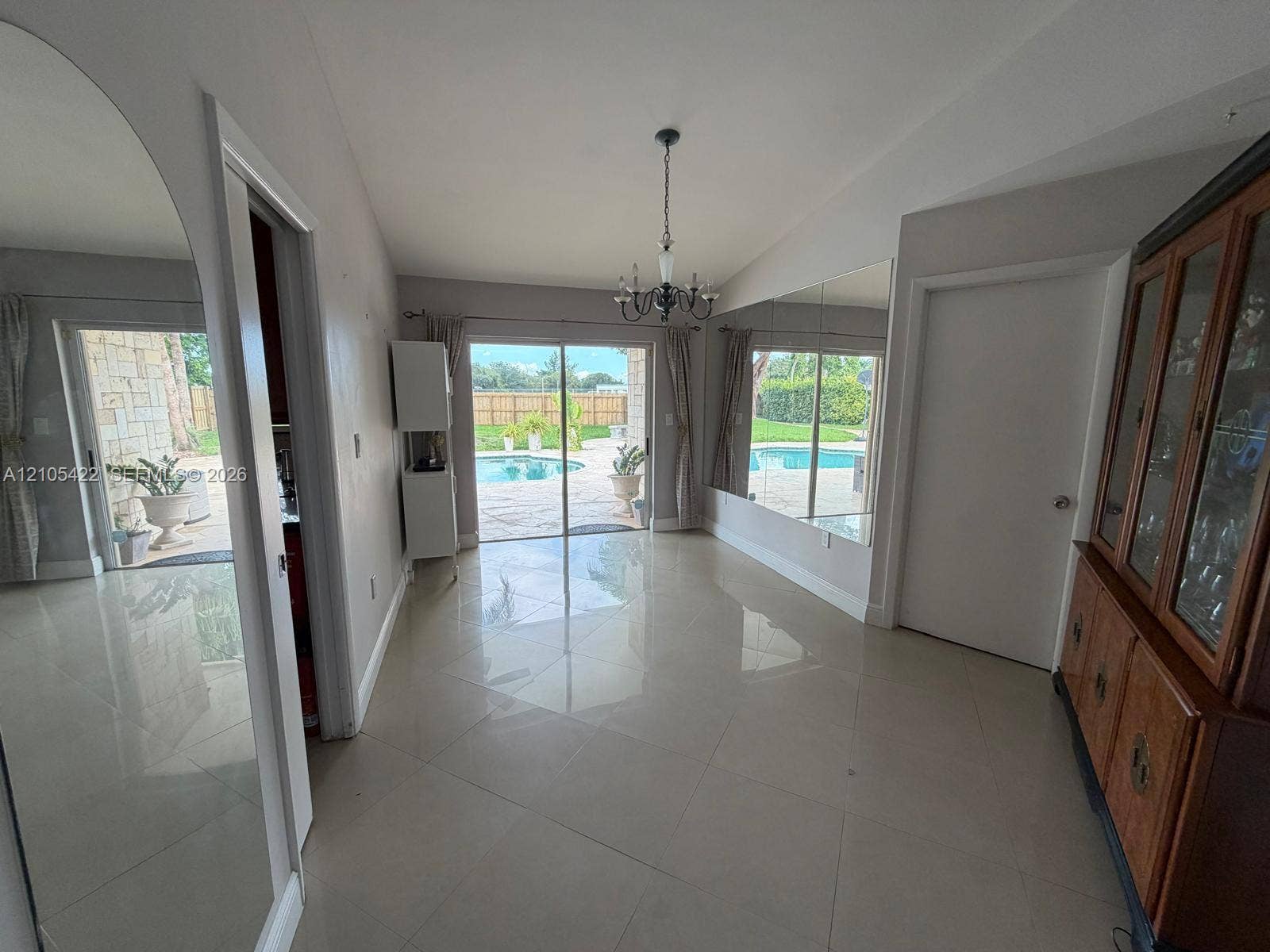 14631 SW 150th Street, Miami, FL 33186 Large-format tile flooring, oversized wall-mounted mirrors, and sliding glass doors with direct exterior access to a paved pool area
