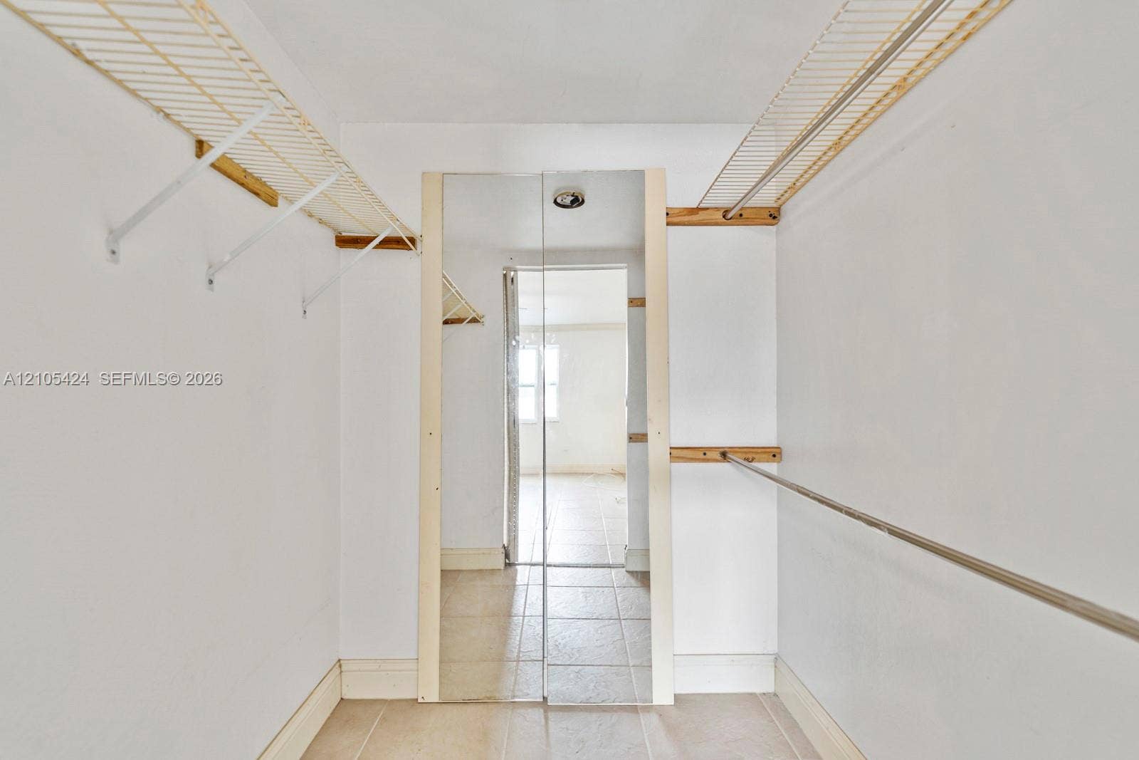 Reach-in closet featuring wire shelving, a metal hanging rod, and tile flooring