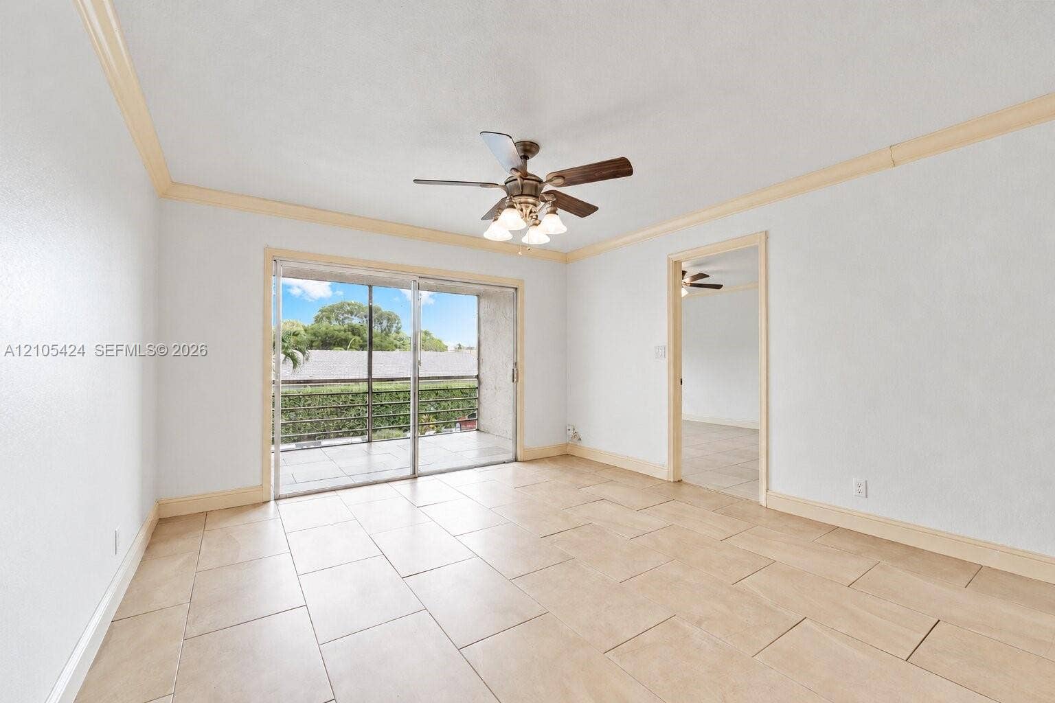Sliding glass door to balcony, tile flooring, ceiling fan, crown molding, and doorway to additional space