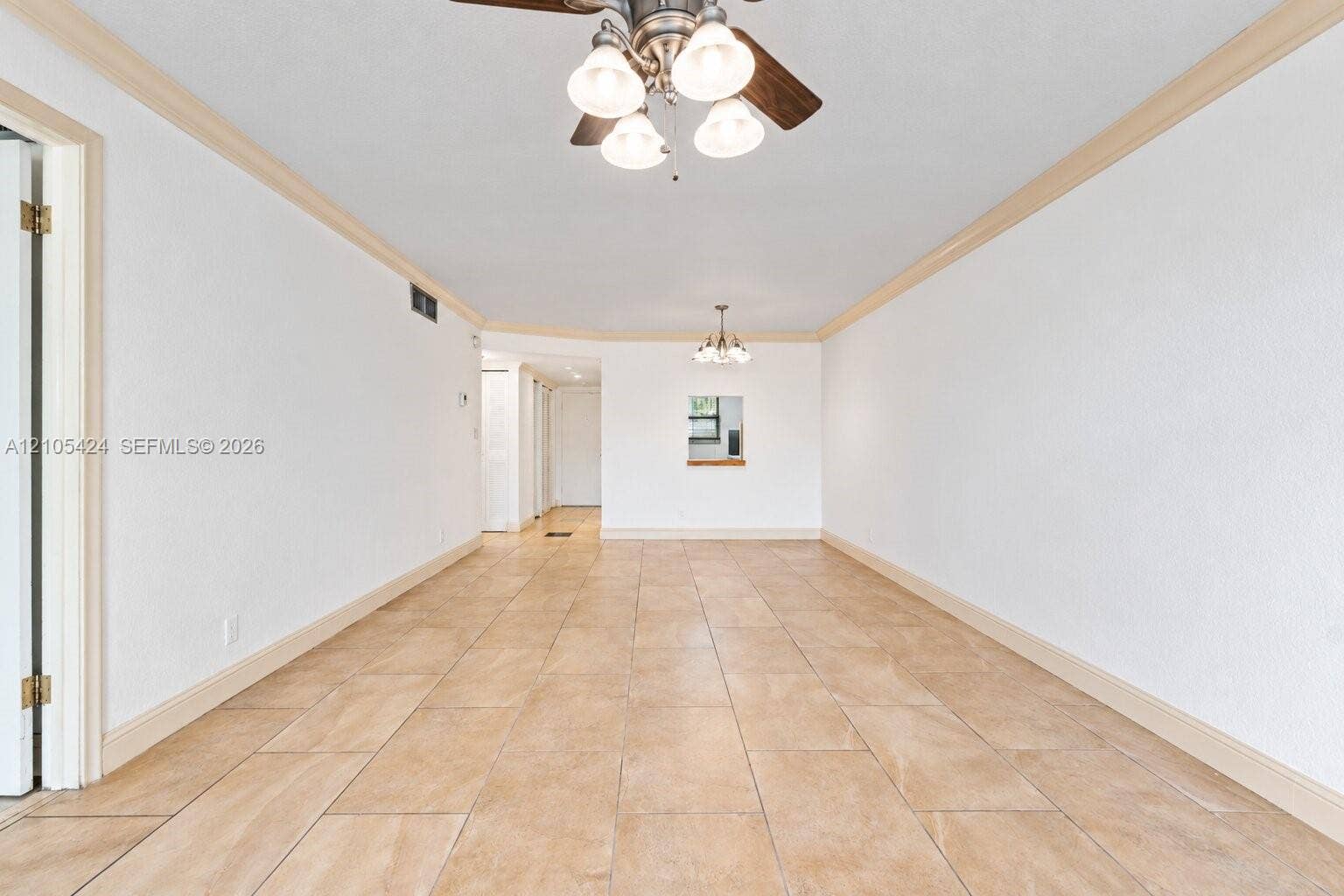 Spacious interior featuring neutral tile flooring, crown molding, and recessed lighting