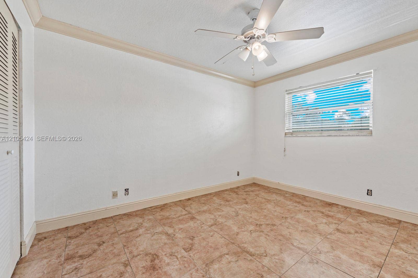 Tile flooring, crown molding, ceiling fan with integrated lighting, window with blinds, and built-in closet