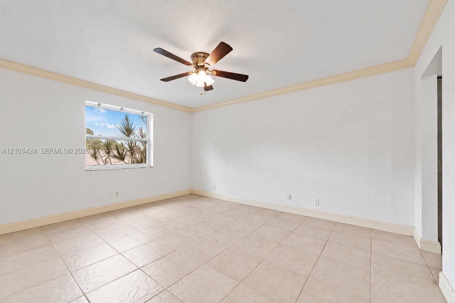Tile flooring, crown molding, a ceiling fan with integrated lighting, and a window providing natural light