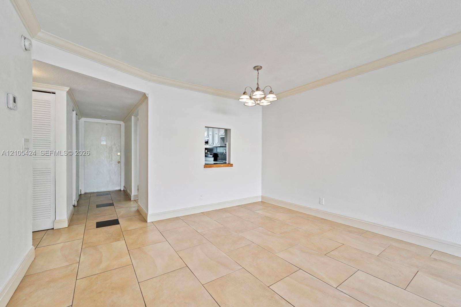 Spacious interior with tile flooring, crown molding, and a pass-through window