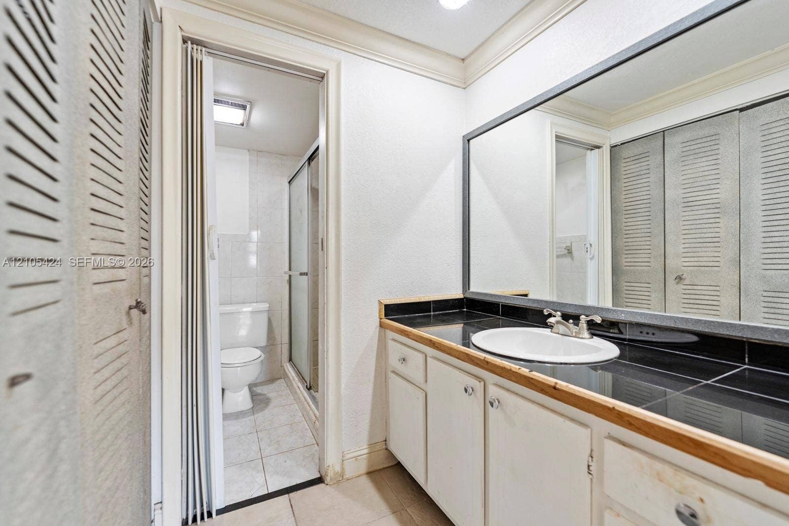 Vanity with a drop-in sink, dark tile countertop, and a large wall-mounted mirror