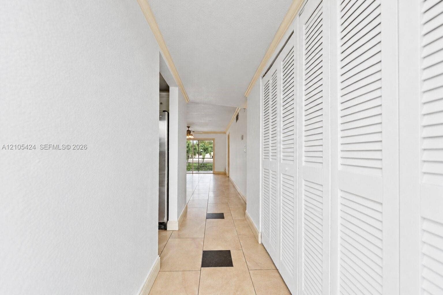 Hallway featuring tile flooring, white louvered closet doors, and crown molding