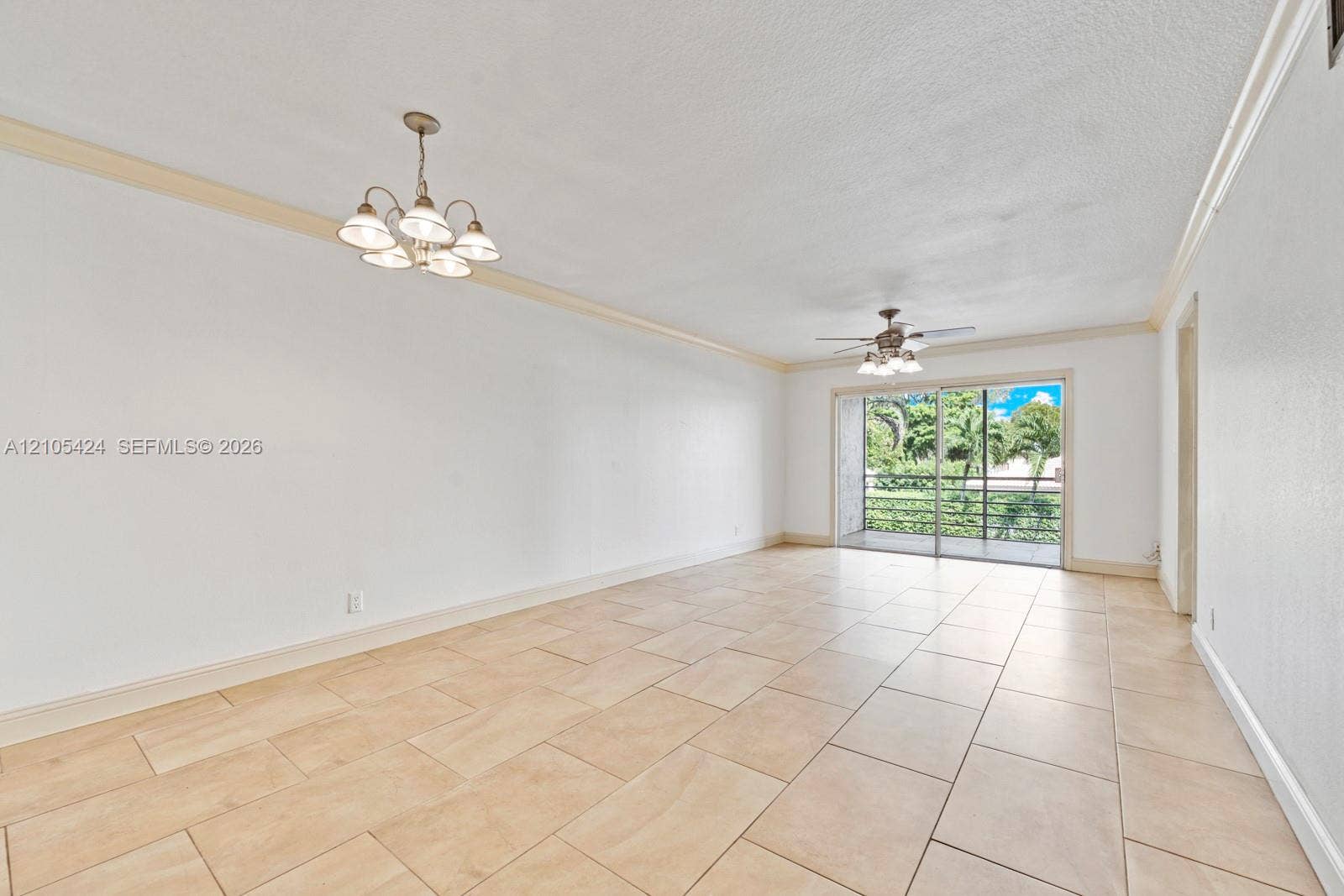 Expansive room featuring large format tile flooring, crown molding, and a five-light chandelier