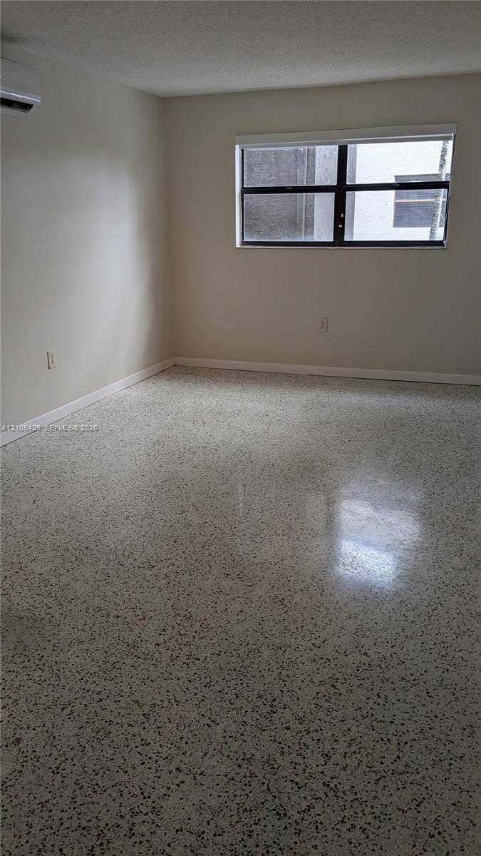Polished terrazzo flooring, neutral wall tones, and a window with a roller shade