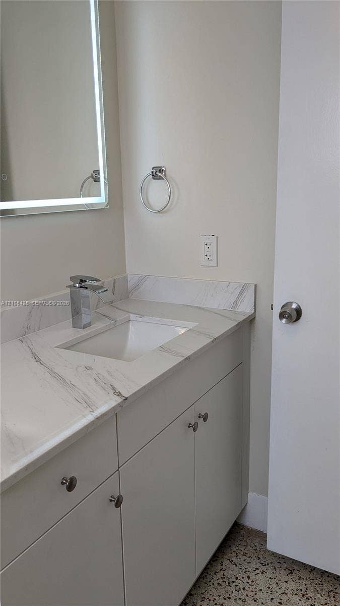 Vanity with a polished chrome faucet, an under-mount sink, and a light-colored countertop
