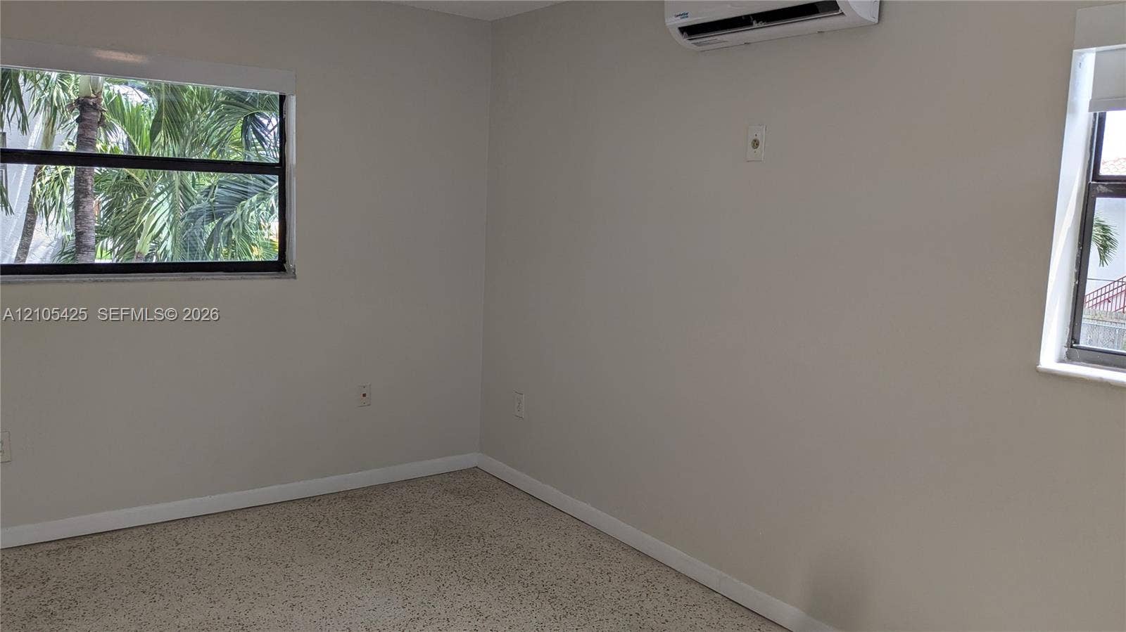 Textured flooring, light-toned walls, and multiple windows with exterior scenery
