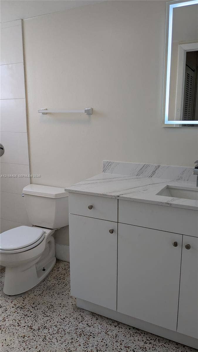 White vanity with a light-toned countertop, integrated sink, and chrome hardware