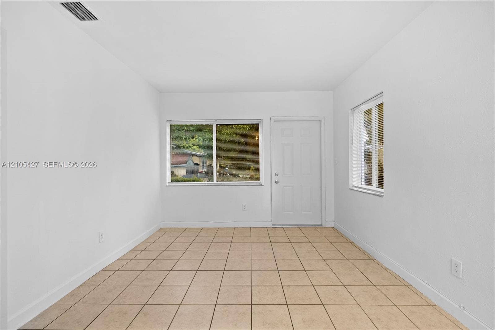 Tile flooring, white painted walls, multiple windows, and a white paneled door