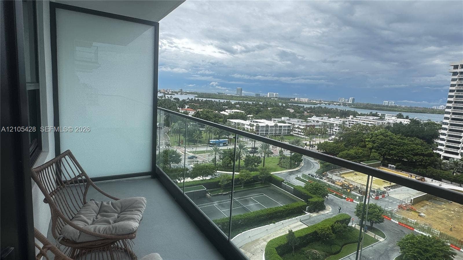 Balcony featuring glass railing, extensive water scenery, and distant urban landscape
