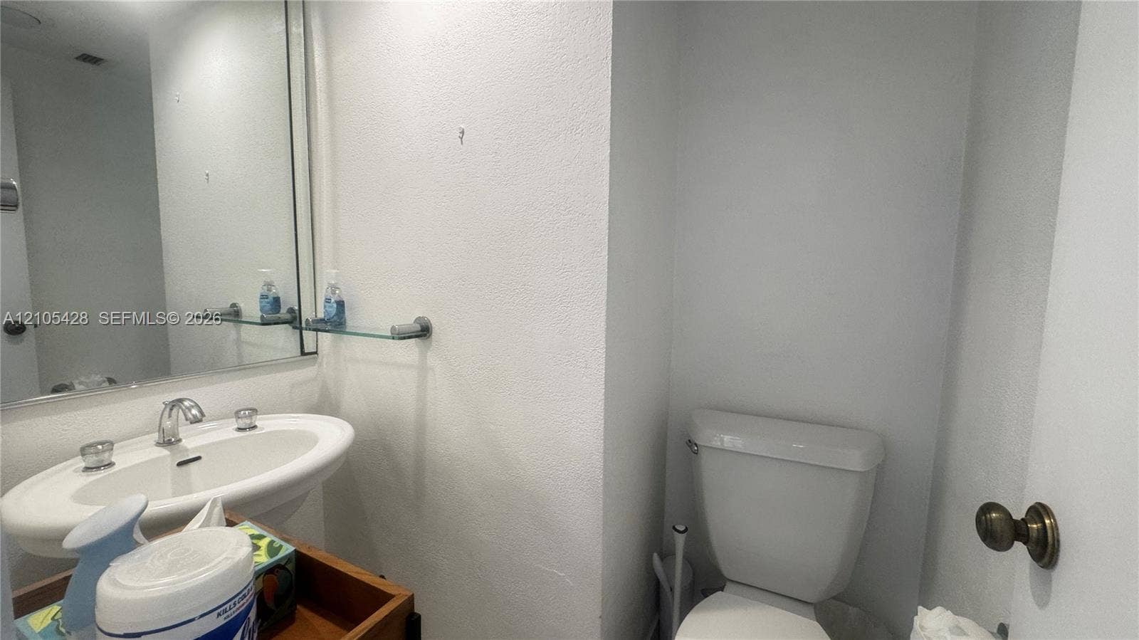 Pedestal sink with chrome-finish faucet, wall-mounted mirror, and glass shelving