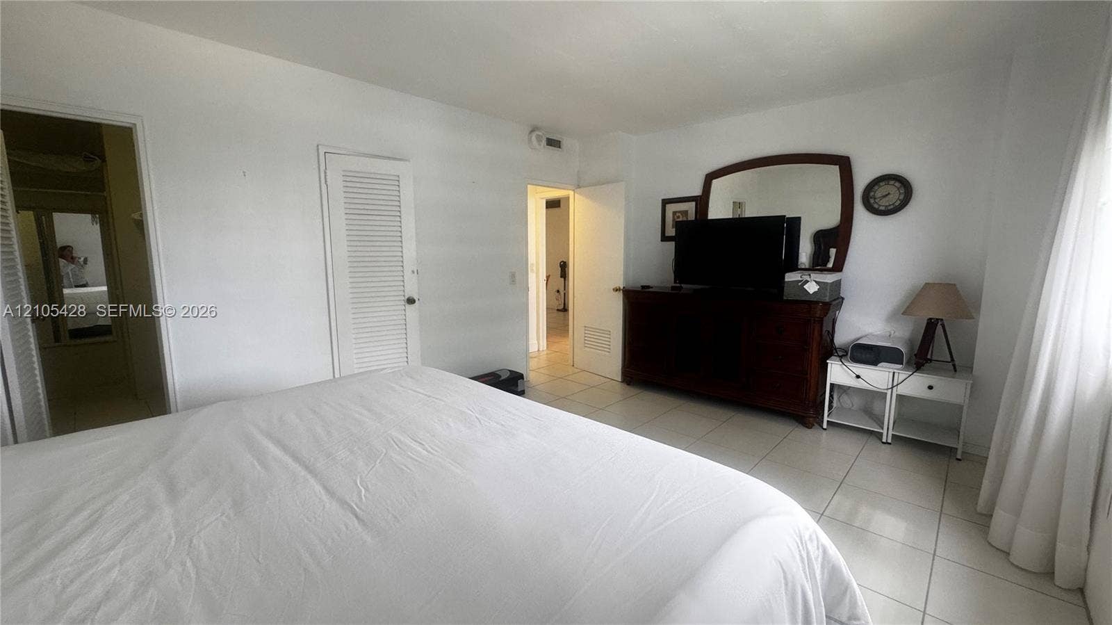 White tile flooring, white painted walls, and a louvered door
