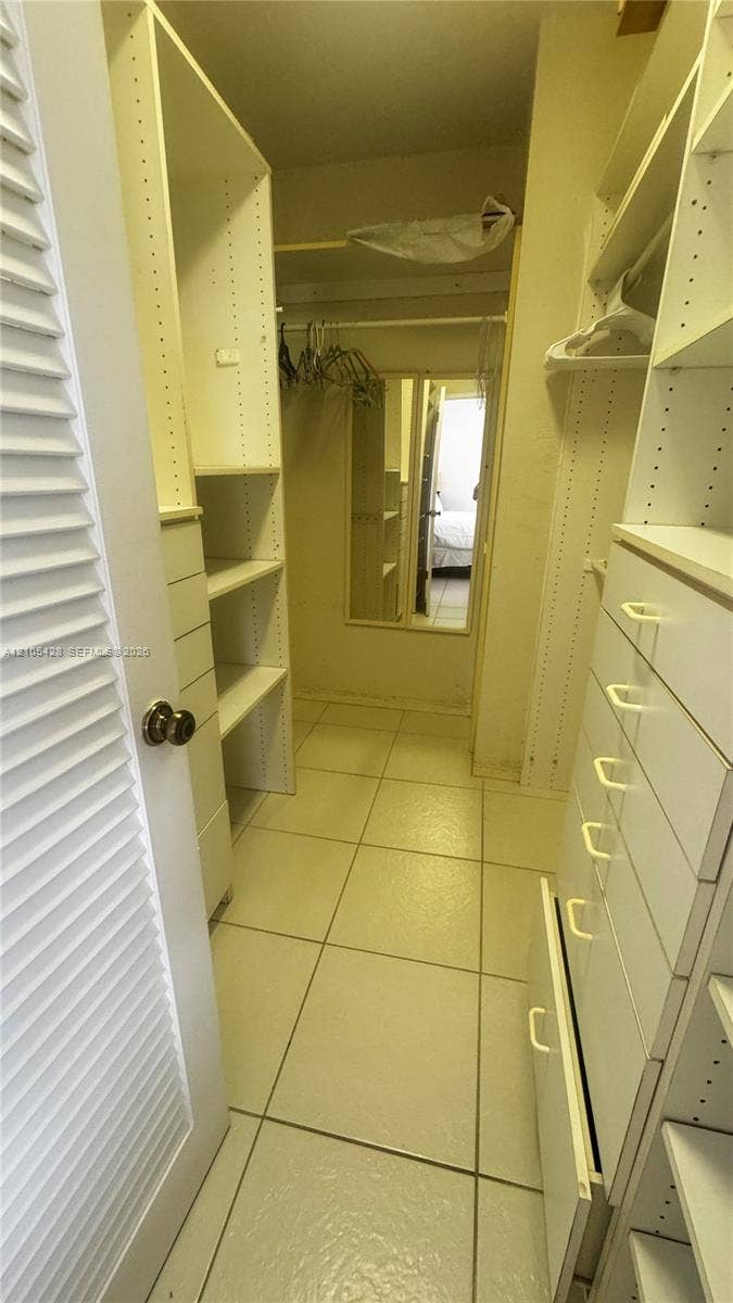 Walk-in closet with built-in shelving, integrated drawers, and a full-length mirror
