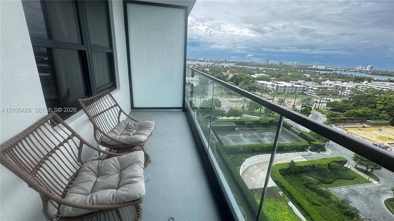 Balcony featuring a glass railing, concrete flooring, and an urban landscape beyond