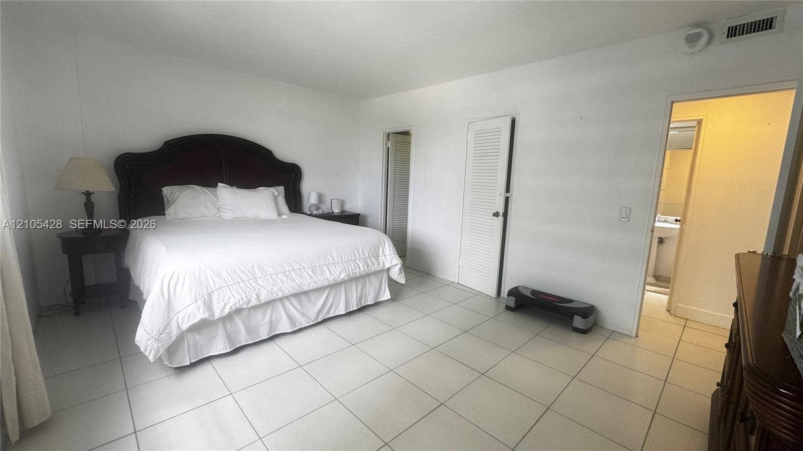 White tile flooring throughout, with a louvered closet door