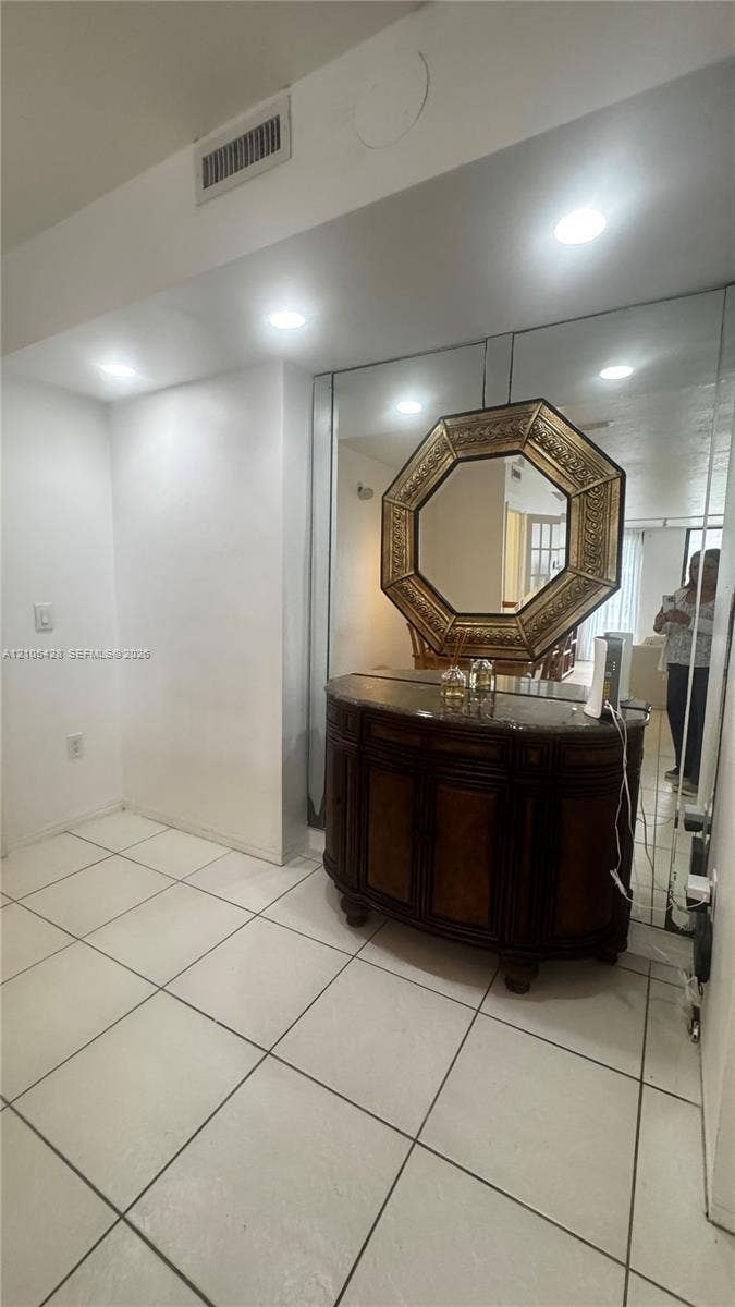 Recessed lighting illuminates the space, featuring large square floor tiles and white walls