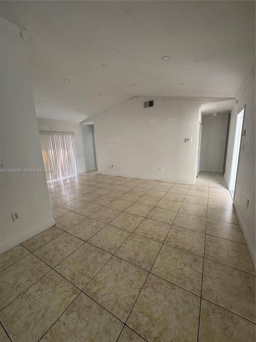 Spacious interior featuring tile flooring, white walls, recessed lighting, and crown molding