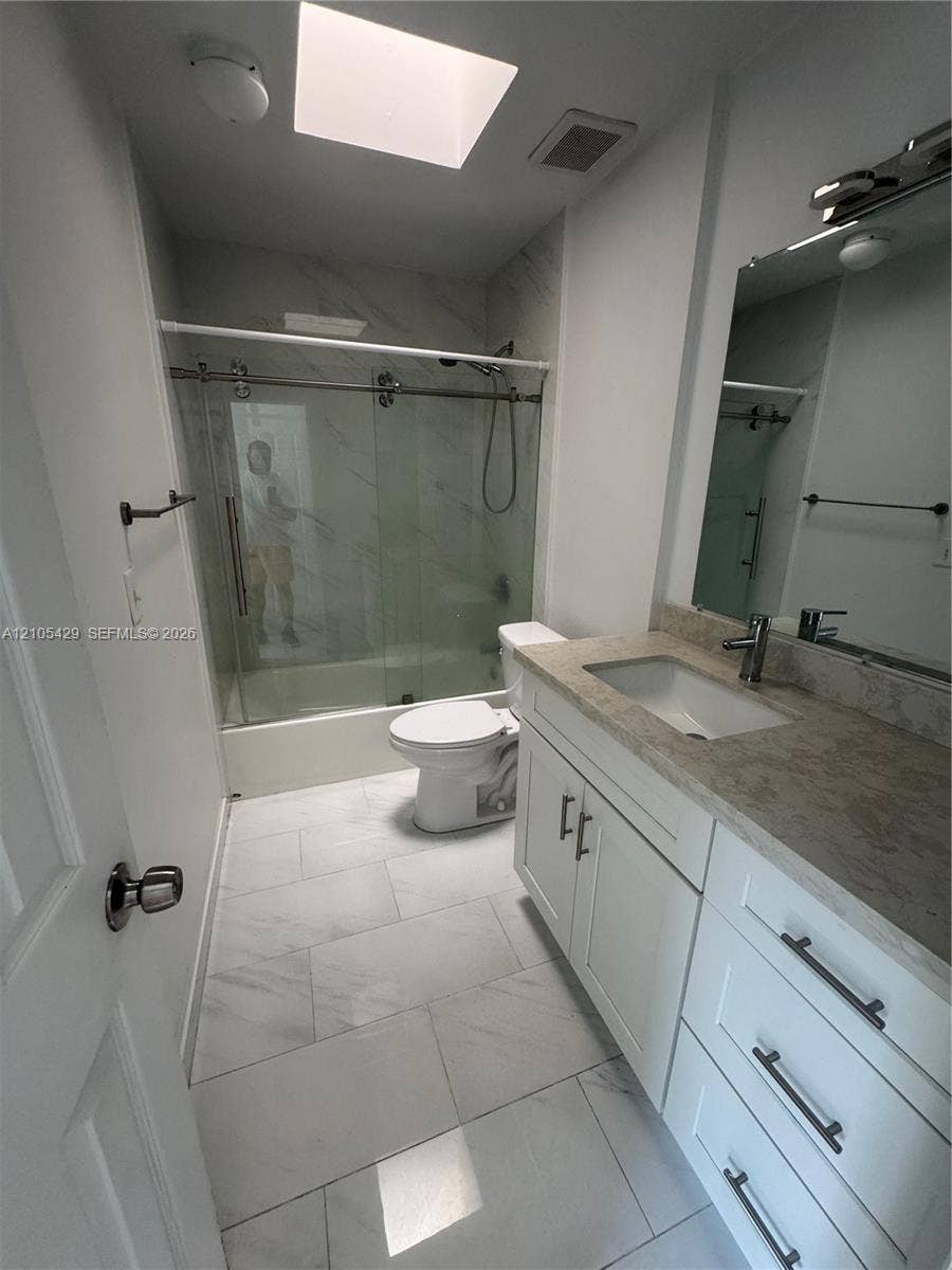White shaker vanity with a light-toned countertop, undermount sink, and matte black hardware
