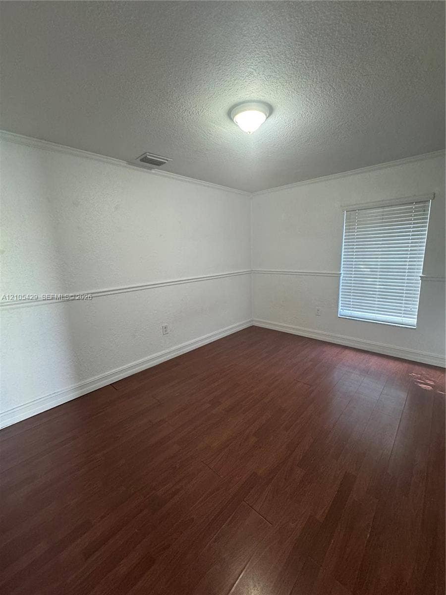 Wood-finish flooring, white walls, and a window with horizontal blinds