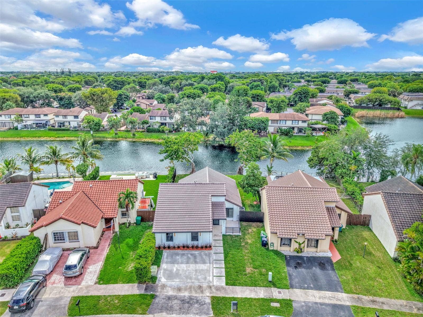 Waterfront residential property featuring a concrete driveway, paver-accented walkway, and tiled roof
