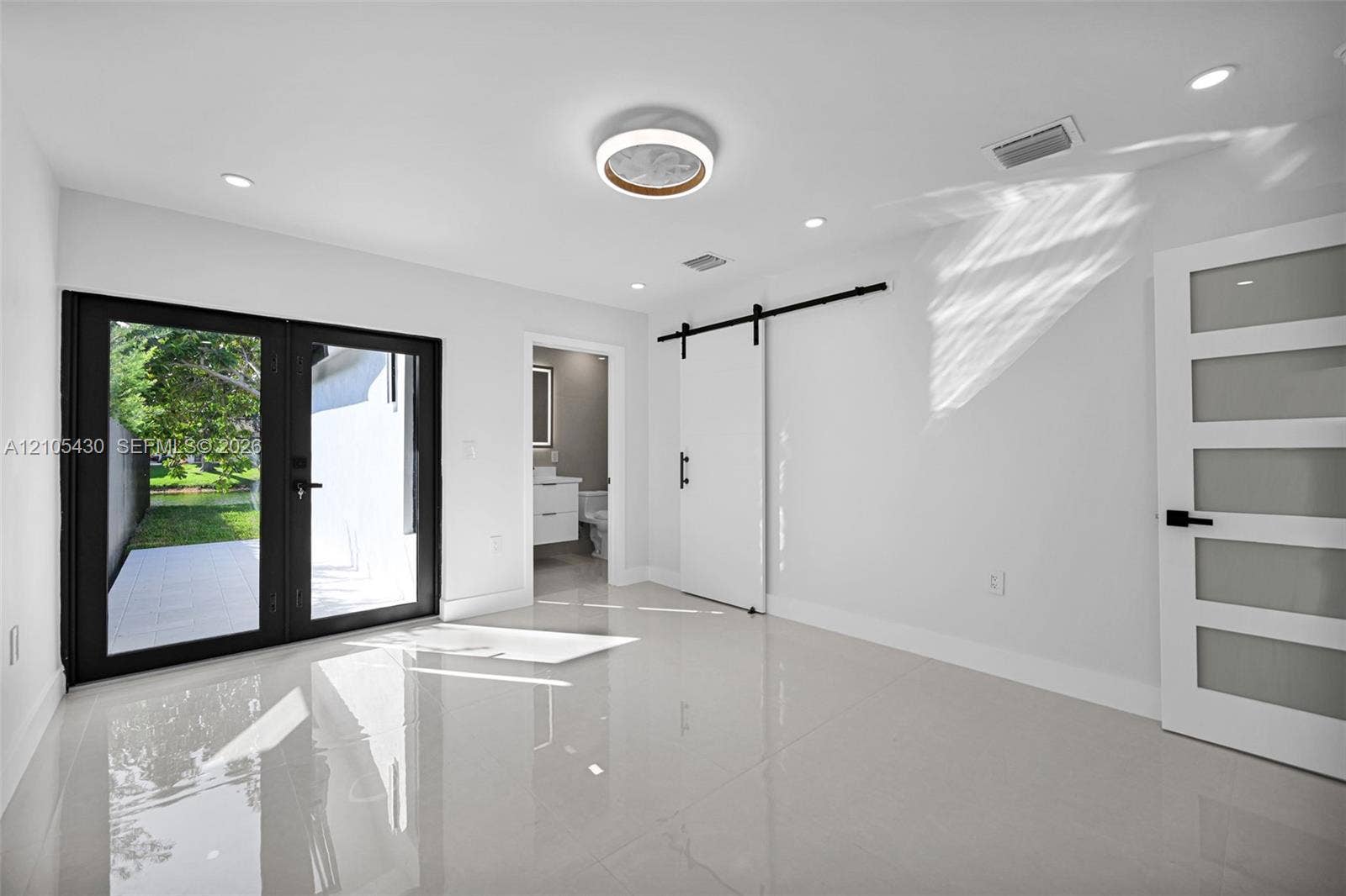 Interior space featuring large-format tile flooring, double glass-paneled exterior doors, a sliding barn-style door, and recessed LED lighting