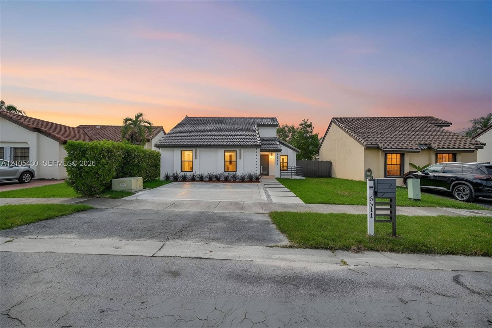 Single-story residence featuring a tile roof, light-toned exterior finish, paver-accented driveway, and manicured landscaping