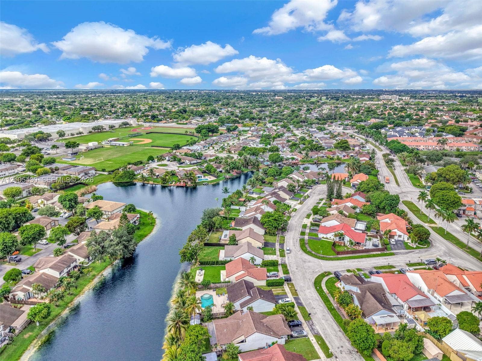 Aerial perspective of waterfront properties featuring meandering canal access and manicured residential grounds