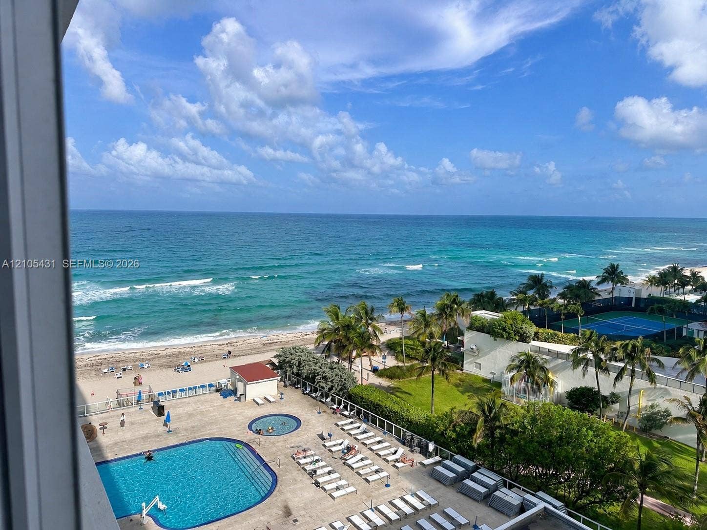 19201 Collins Avenue, #707, Sunny Isles Beach, FL 33160 Expansive oceanfront setting featuring a sandy beach, outdoor swimming pool, tennis court, and mature palm trees