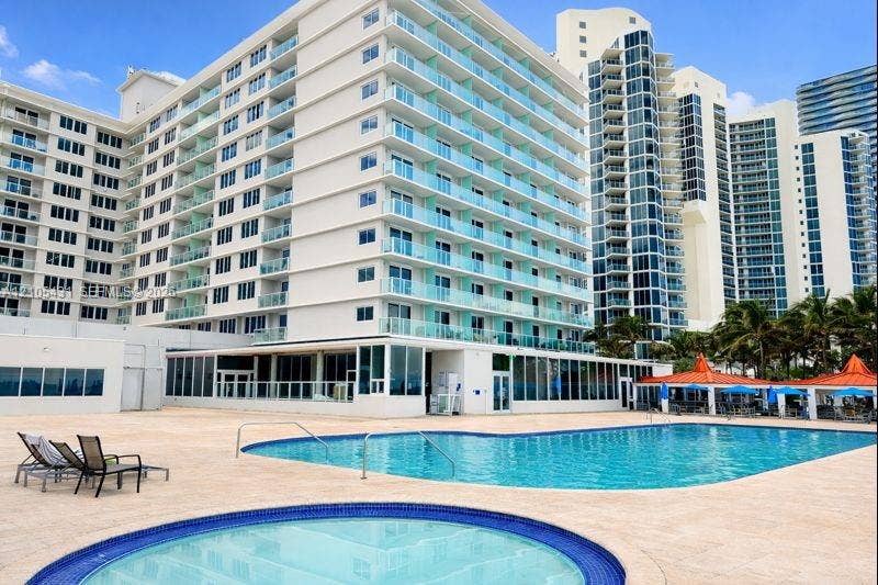 19201 Collins Avenue, #707, Sunny Isles Beach, FL 33160 Resort-style pool area featuring a large swimming pool, circular hot tub, and expansive paver deck