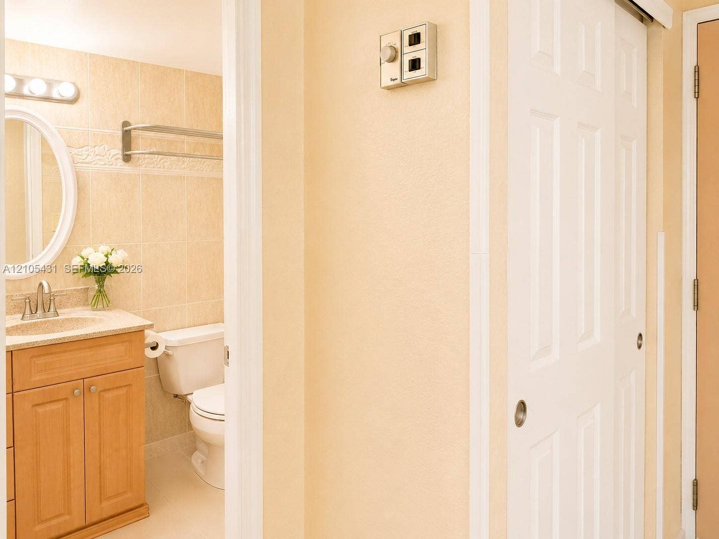 19201 Collins Avenue, #707, Sunny Isles Beach, FL 33160 Bathroom with a wood-finish vanity, light-toned countertop, oval mirror, and tile-surround wall